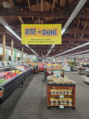 Supermarket interior with a 'Rise and Shine' coffee sign above the produce section.